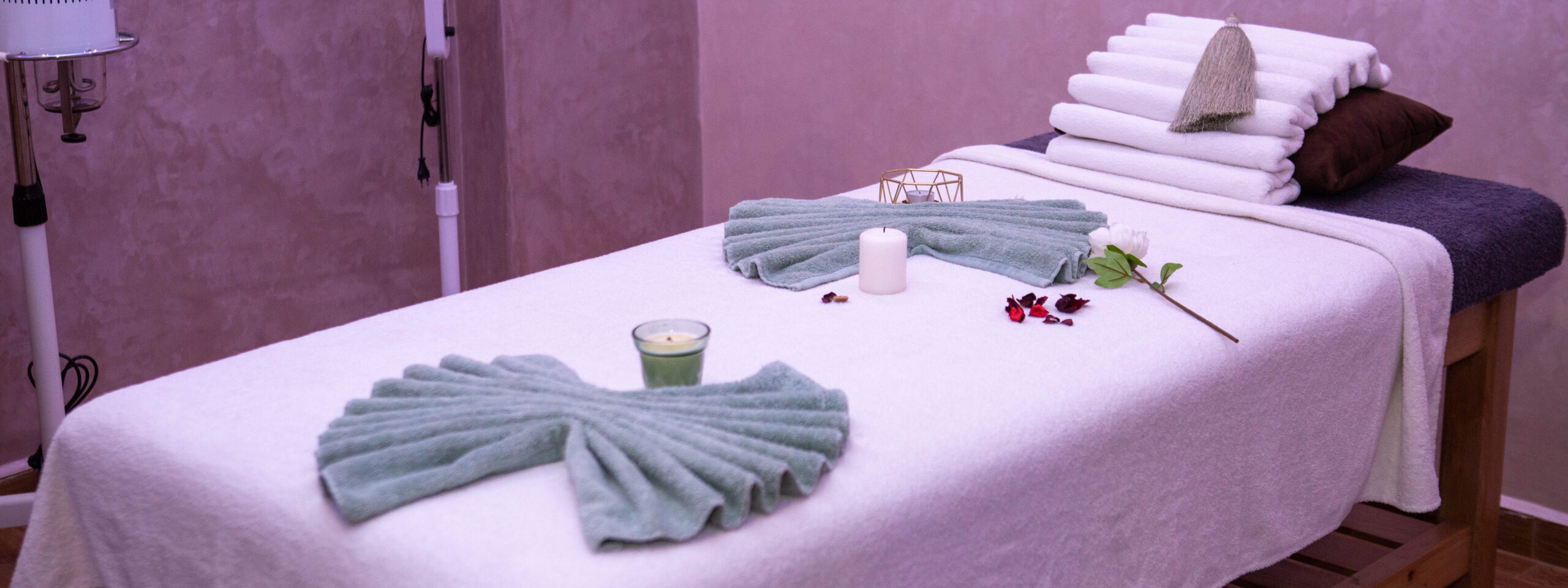 Table de massage décorée avec des serviettes et bougies.